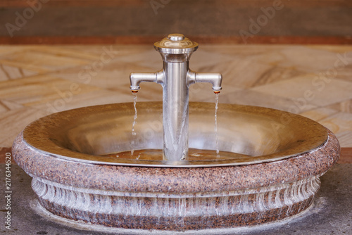 Canvastavla Elegant stone drinking fountain with dual steel taps in public space