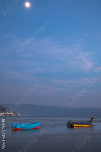 Konstfotografi Two colorful fishing boats moored in calm water under a moonlit sky