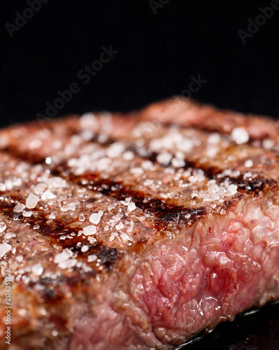 Macro close-up of charred steak surface with salt crystals and meat fibers