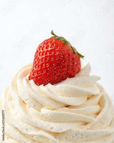 Macro close-up of piped cream frosting swirl with fresh strawberry on top