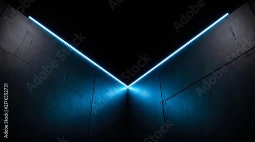 V shaped glowing blue neon light strip mounted on dark gray modern architectural wall corner for minimalist futuristic interior design and studio background.