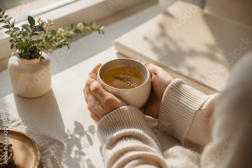 Peaceful morning ritual holding a warm ceramic mug by a sunlit window