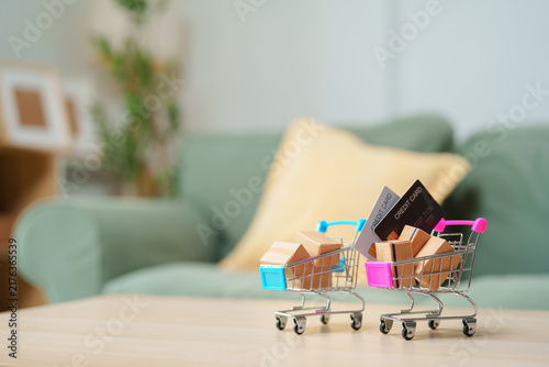 Obraz na płótnie Shopping carts with package boxes and credit cards on table in home interior wit