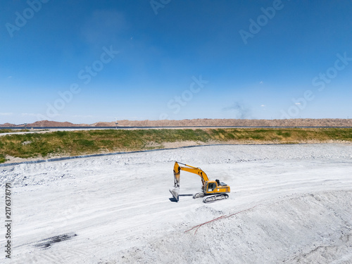 yellow excavator working on white sand ground
