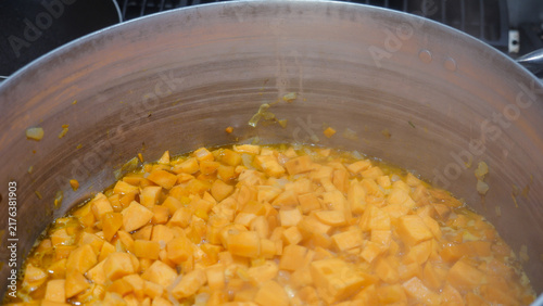 Foto Sweet potato cubes are simmering in a large aluminum pot on a commercial gas sto