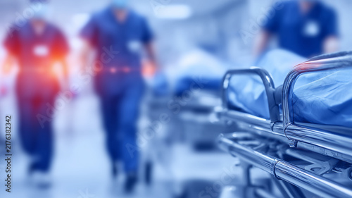 Hospital gurney in an emergency corridor with medical staff approaching depicts urgent patient care and rapid healthcare response.

