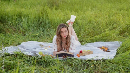 Young Woman Enjoying a Picnic While Reading in a Sunny Field