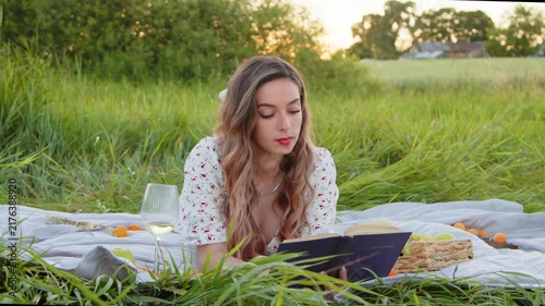 A Young Woman Enjoys a Peaceful Picnic Outdoors While Reading a Book