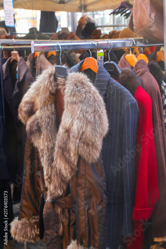 Vintage winter coats and fur jacket hanging on rack at outdoor street flea market