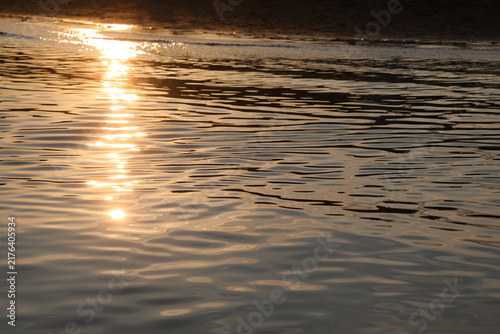 Картината върху платно Golden sunset reflection on calm sea water surface ripples