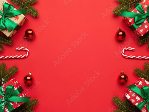 Christmas gifts with green ribbons and candy canes on festive red surface