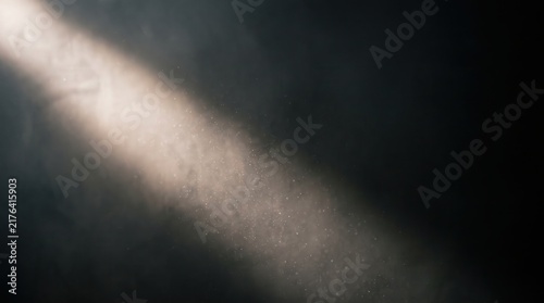A diagonal beam of light cutting through dusty air against a dark background
