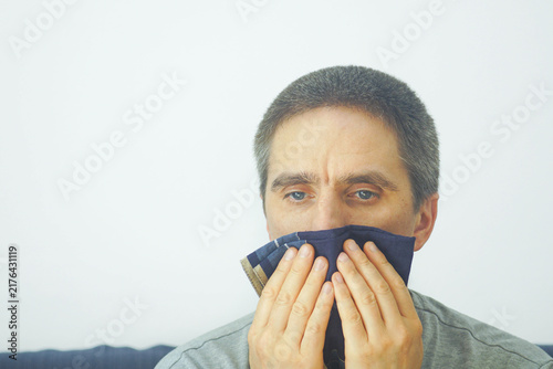 Fotografía Exhausted man covering nose and mouth with reusable cloth handkerchief