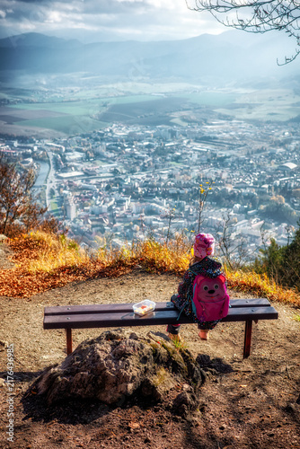 Child hiker resting on Cebrat hill with panoramic view of Ruzomberok and Liptov landscape