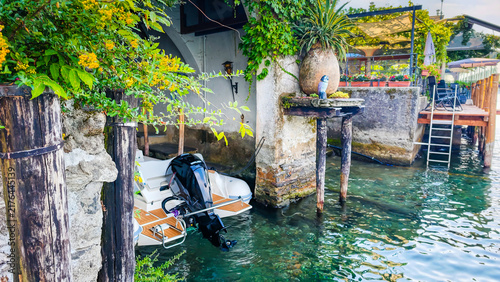 Traditional Italian lakeside atmosphere with a motorboat stored in a waterside boathouse garage, capturing the charm of lakefront living and boating on the Italian Lakes district