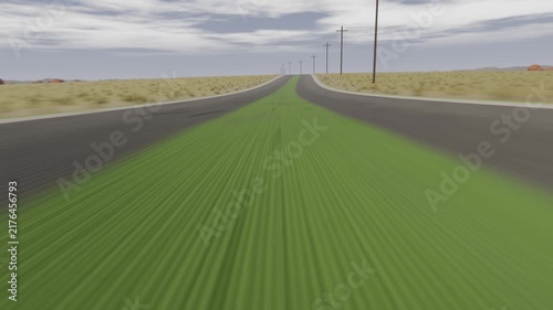 Moving low camera rolling down rural 2-lane road, showing green strip, poles drawing eye to horizon