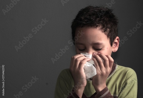 flu epidemic with child blowing nose after catching a cold with people on dark background stock image stock photo