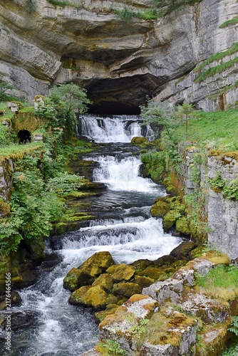 Source de la Loue jaillissant d'une caverne sous une falaise, Ouhans, France.