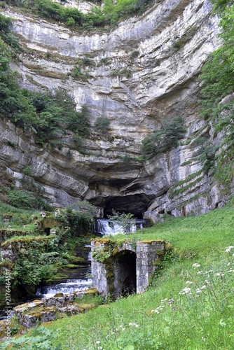 Source de la Loue jaillissant d'une caverne sous une falaise, Ouhans, France.