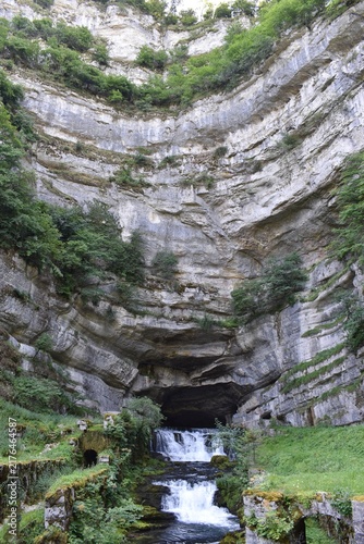 Source de la Loue jaillissant d'une caverne sous une falaise, Ouhans, France.