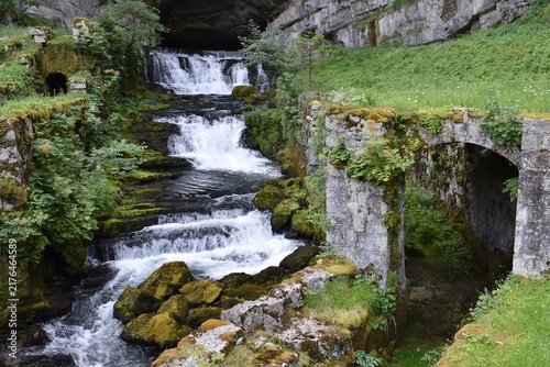 Source de la Loue jaillissant d'une caverne sous une falaise, Ouhans, France.