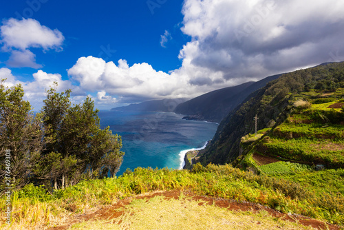 фотографія Panoramic ocean view from a verdant cliffside under a blue sky with clouds in Ma