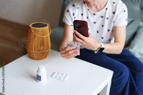 Woman checks medication while using smartphone for AI health advice, concept of self-treatment and artificial intelligence instead of doctor visit.