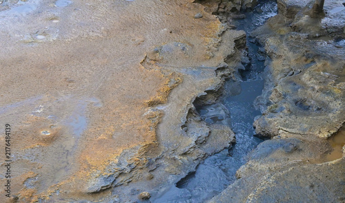 Obraz na płótnie Close-up view of mineral-rich geothermal terrain at Hverir in Iceland, with a narrow geothermal channel flowing through eroded volcanic ground and colorful mineral deposits