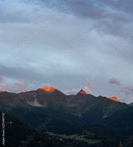 Bild auf Leinwand Alpenglow on Mountain Peaks Above Forested Valley at Sunset Panorama