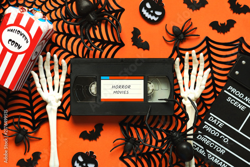 Top view of VHS video tape cassette with the text horror movies alongside Halloween popcorn, clapperboard and Halloween party decoration. Halloween movies concept