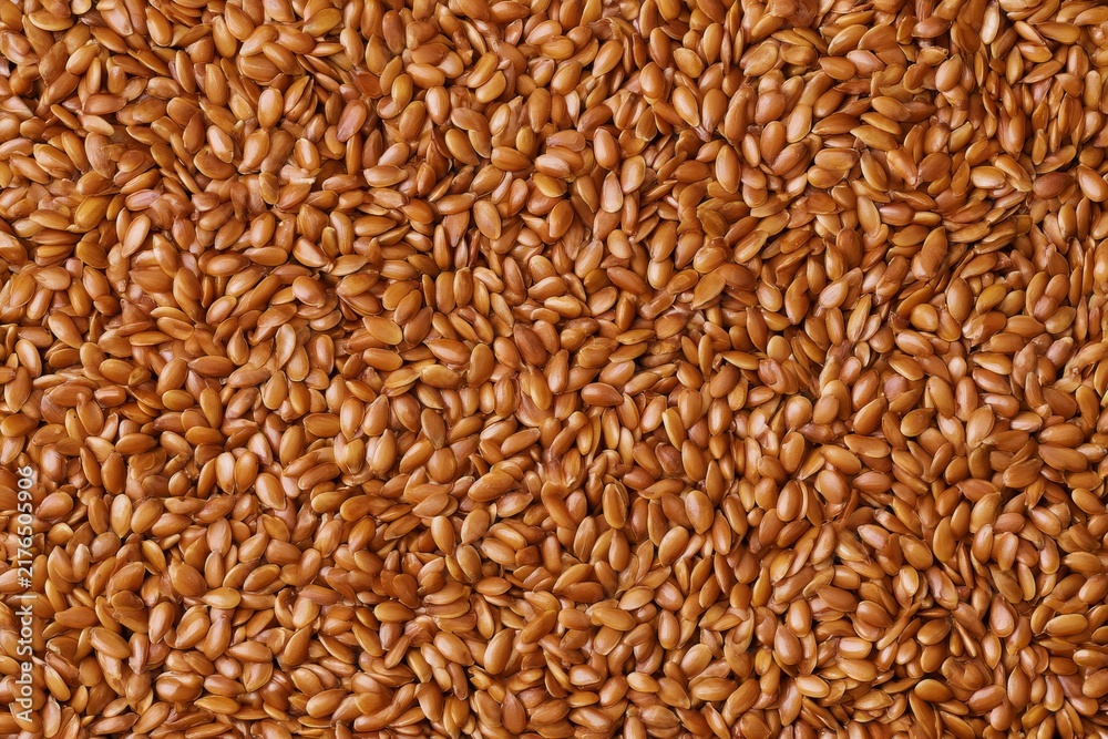 Fototapeta premium Brown flaxseeds spread out on a flat surface, showing the texture and color of the seeds