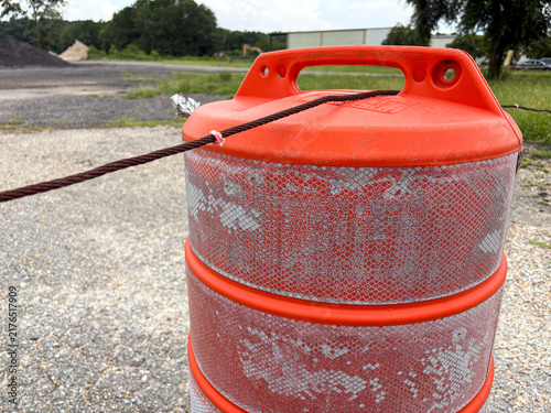 Close-up of orange construction traffic barrel with reflective stripes and copy space