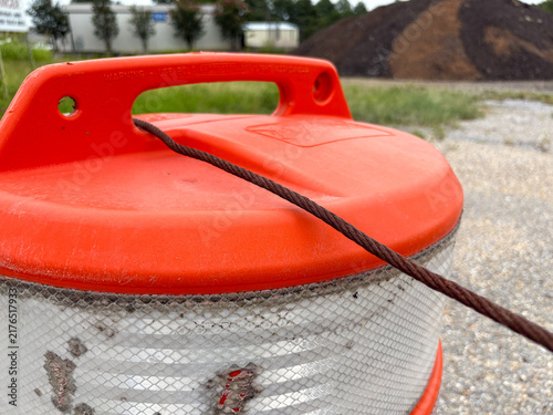 Close-up of orange construction traffic barrel with reflective stripes and copy space