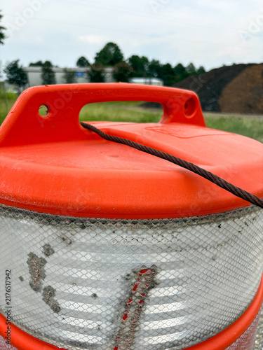Close-up of orange construction traffic barrel with reflective stripes and copy space