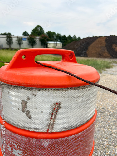 Close-up of orange construction traffic barrel with reflective stripes and copy space