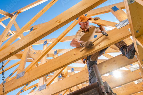 Carpenter working among timber roof trusses during construction