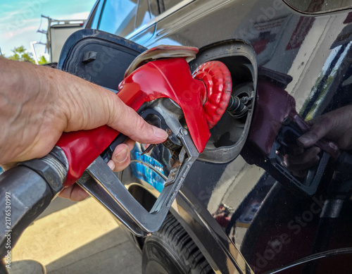 Cuadro en lienzo A hand holding a gas station pump nozzle while pumping gasoline into an automobi
