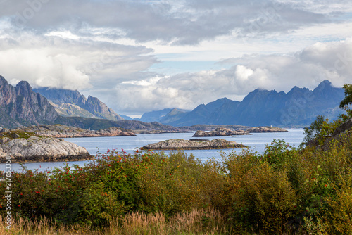 Spektakuläre Küstenlandschaft mit Schäreninseln im Fjord vor einer markanten Bergkette unter dramatischem Wolkenhimmel, Henningsvær, Norwegen, Europa