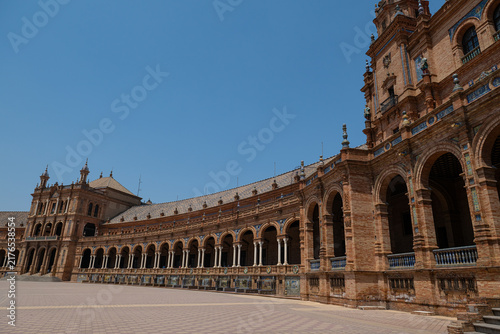 The curved caravanserai architecture of Seville’s Plaza de España, its colonnaded corridors, and the view of the spacious plaza.