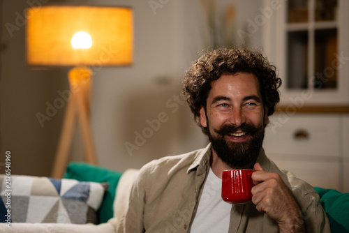 Принти на полотні Happy man relaxing on sofa holding coffee mug