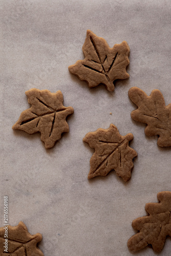 Autumn leaves biscuits arranged flat on white baking paper. 