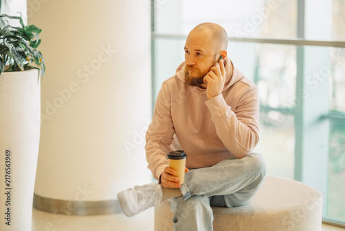 Man taking a phone call with a coffee in a mall