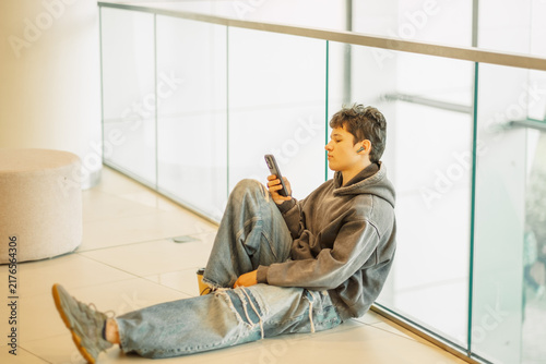 Teenage boy with legs stretched out on a mall floor