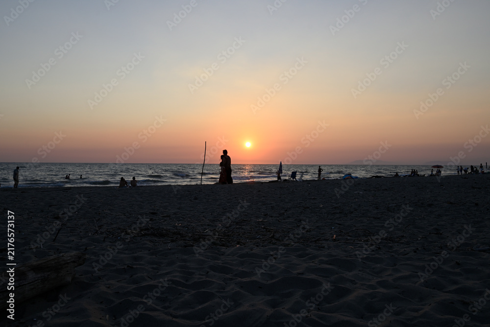 Obraz premium People enjoying sundown at tuscany beach. Togetherness at italian beach. Marina di Torre del LAgo, Tuscany, Italy, Europe.