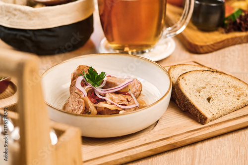 Plate of meat dish with onions and bread on wooden serving tray