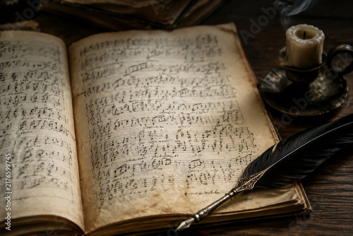 An ancient, open musical score with a quill pen and an extinguished candle.