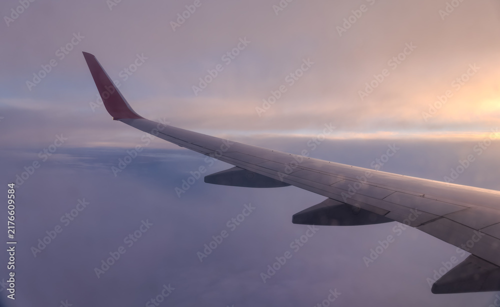Fototapeta premium Beautiful salmon dawn and the wing of an airplane above the clouds.