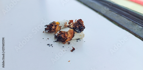 фотографія Discarded Cigarette Butt with Scattered Ashes on a Surface.