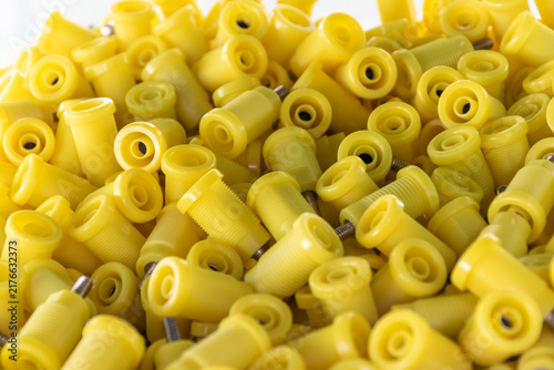 Фотография Close up of numerous yellow plastic threaded components metal inserts arranged p