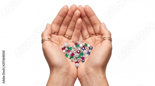 Hands holding a heart shape made of colorful loose diamonds and precious gemstones.